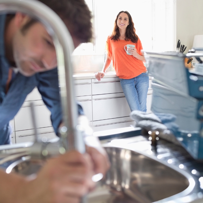 Plumber fitting a kitchen tap and sink in a Kingston home